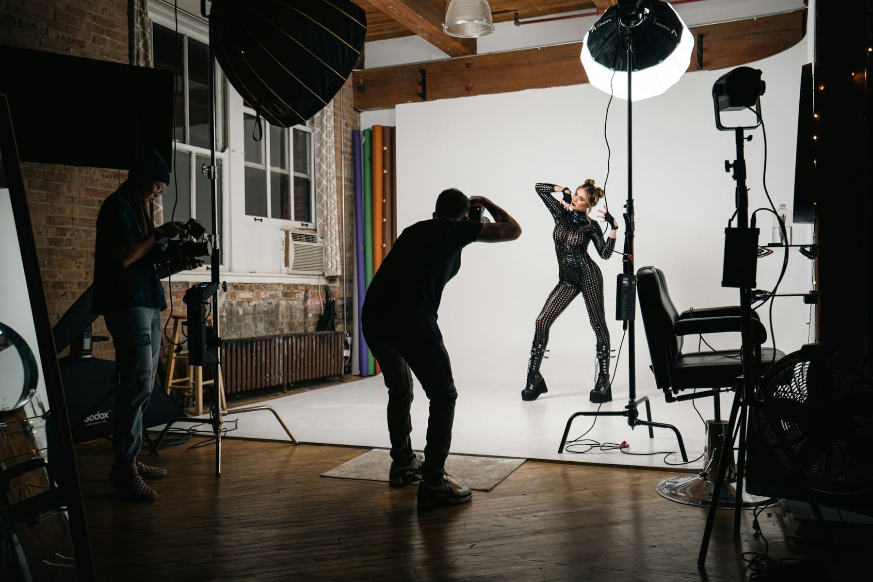 Photographer and videographer filming a model on a studio set with professional lighting