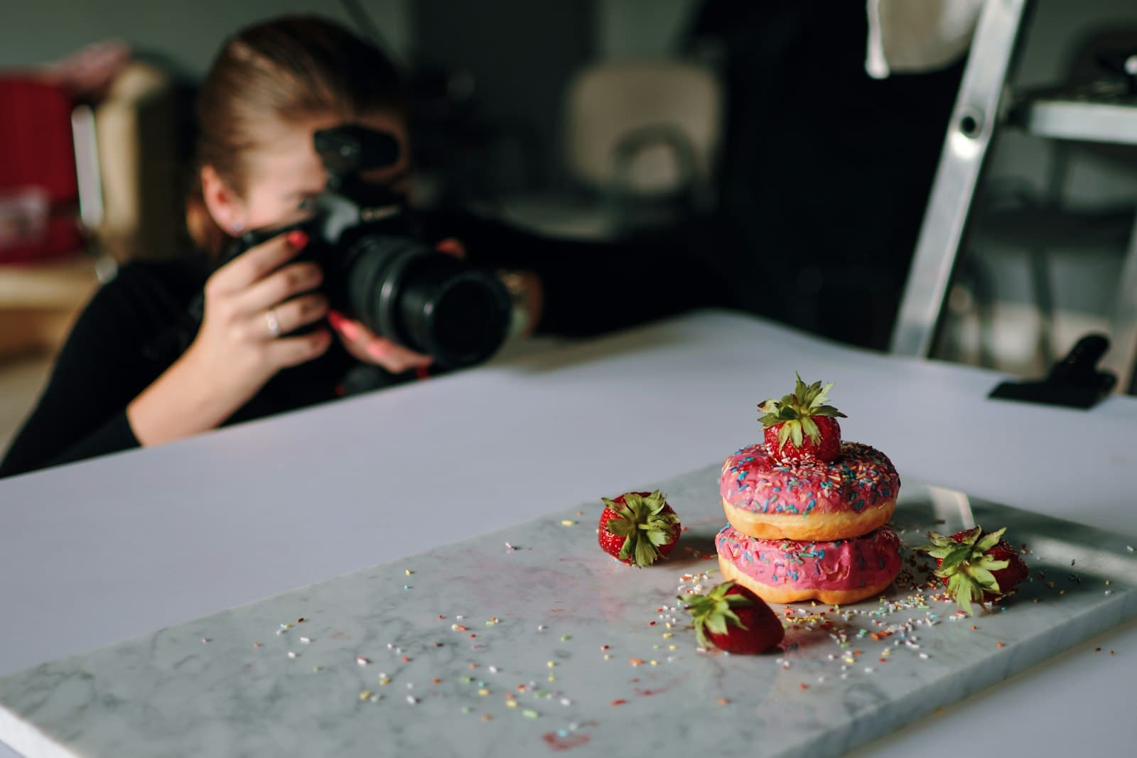 Photographer shooting a styled food commercial with donuts on a marble surface in a studio